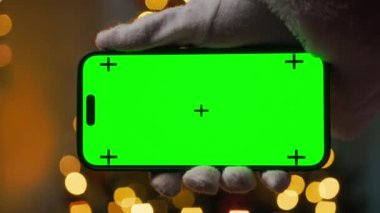 Noel Baba yeşil ekranlı akıllı telefonu tutuyor.