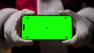 Noel Baba yeşil ekranlı akıllı telefonu tutuyor.