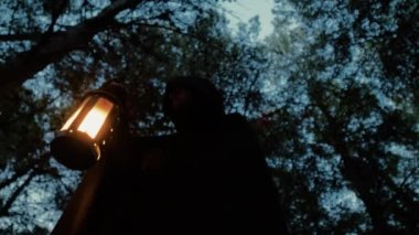 Koyu renk elbiseli bir adam ve yürüyen ve arayan bir fener. 