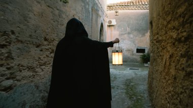 Koyu renk elbiseli bir adam ve yürüyen ve arayan bir fener. 