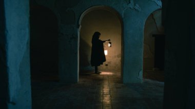 Koyu renk elbiseli bir adam ve yürüyen ve arayan bir fener. 