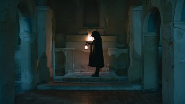 Koyu renk elbiseli bir adam ve yürüyen ve arayan bir fener. 