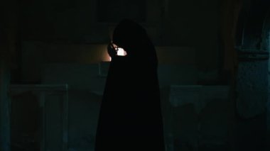 Koyu renk elbiseli bir adam ve yürüyen ve arayan bir fener. 