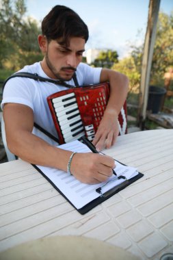 Adam akordiyon çalışıyor ve kağıtta izliyor. .