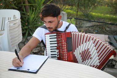 Adam akordiyon çalışıyor ve kağıtta izliyor. .