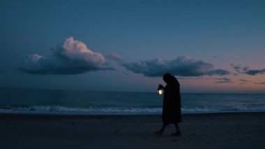 Koyu renk elbiseli bir adam ve yürüyen ve arayan bir fener. 