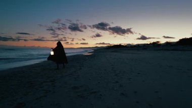 Koyu renk elbiseli bir adam ve yürüyen ve arayan bir fener. 