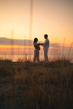 Bir çift gün batımında bebek paylaşımı bekliyor..