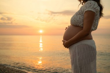 Bir çift gün batımında bebek paylaşımı bekliyor..