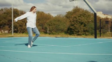 Dansçı basketbol sahasında hareket ediyor ve pratik yapıyor. 