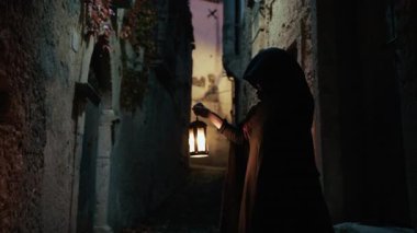 Koyu renk elbiseli bir adam ve yürüyen ve arayan bir fener. 