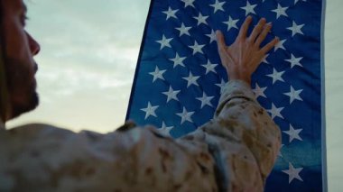 Üniformalı asker bayrağa eliyle dokunuyor.. 