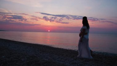 Bir çift gün batımında bebek paylaşımı bekliyor..