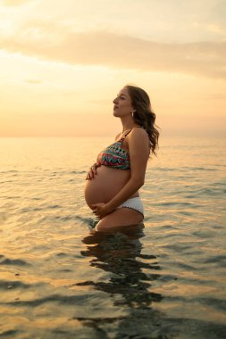Bir çift gün batımında bebek paylaşımı bekliyor..