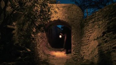 Koyu renk elbiseli bir adam ve yürüyen ve arayan bir fener. 