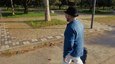 Yolculuk sırasında elinde bavuluyla parkta bir adam..