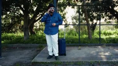 Otobüsü beklerken telefonda konuşan bir adam. .