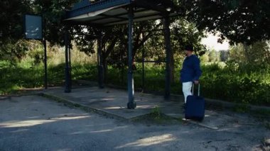 Bavullu adam otobüs durağında bekliyor..