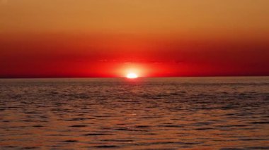 Kırmızı güneş topu gün batımında ufkun arkasında batıyor. Yüksek kalite 4k görüntü