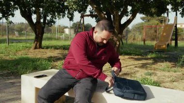 Muhbir, parkta çalışmaya başlamak için dizüstü bilgisayarı alıyor.. 