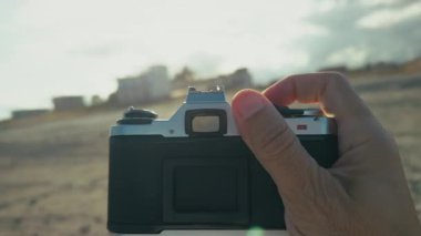 Adam sahilin yakınındaki kasabaya eski bir kamerayla fotoğraf çekiyor, Pov. . 