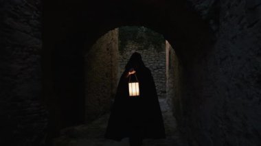 Koyu renk elbiseli bir adam ve yürüyen ve arayan bir fener. 