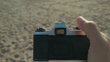 Kumsalda vintage kamera kullanan bir adamın elleri ve pov 'u. . 