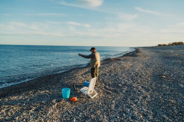 Denizde güneşli bir günde balık tutan adam 