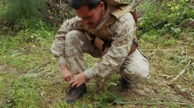 Yaralı ayağından bir şey çıkaran adam..