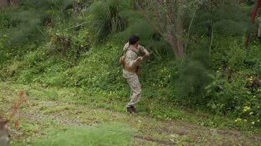 Elinde sopayla çimenlere bakan asker. . 