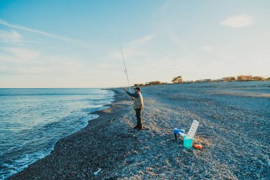 Denizde güneşli bir günde balık tutan adam 