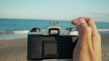 Adam eski kamerayla denizin fotoğraflarını çekiyor, Pov. . 