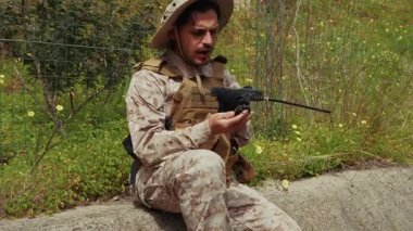 Asker yolun kenarında oturuyor ve ekibiyle iletişim kuruyor.. 