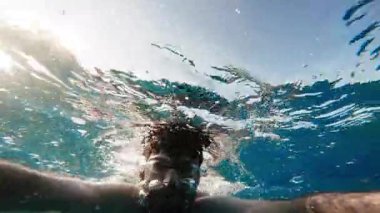 Çocuk denizde yüzüyor.