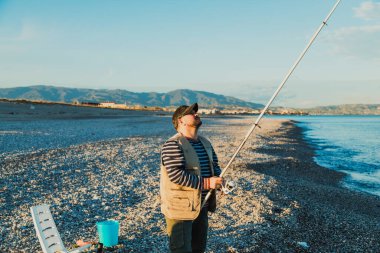 Denizde güneşli bir günde balık tutan adam 