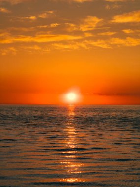 Güneş doğarken okyanus suyundaki portakal yansımaları .