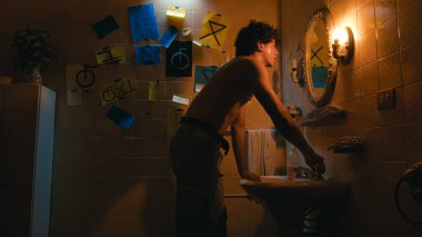 Banyodaki aynanın önünde yüzünü yıkayan adam.. 