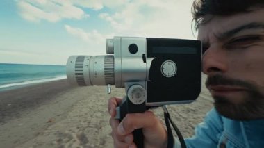 Plajda genç bir adamın kullandığı eski bir kameraya kilitlenmiş. . 