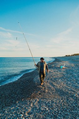 Denizde güneşli bir günde balık tutan adam 