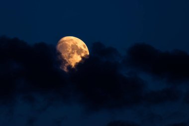 Gece gökyüzünde bulutlarla parlayan dolunay..