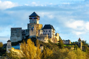 Batan güneşin ışığıyla aydınlatılan görkemli Trencin kalesi bir tepenin üzerinde duruyor..