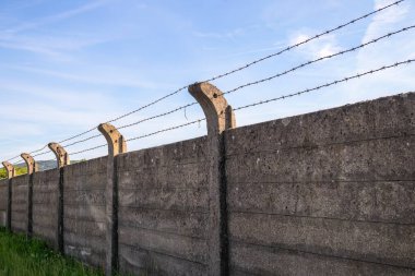 Özel mülkü çevreleyen beton çitler. Dikenli teller çitin üstüne gerilmiş..