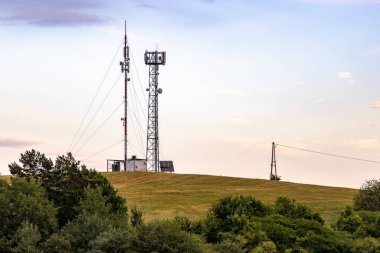 Tepenin tepesinde bir telekomünikasyon kulesi ve direği var. Yanlarında onlara elektrik sağlayan ahşap bir kule var..