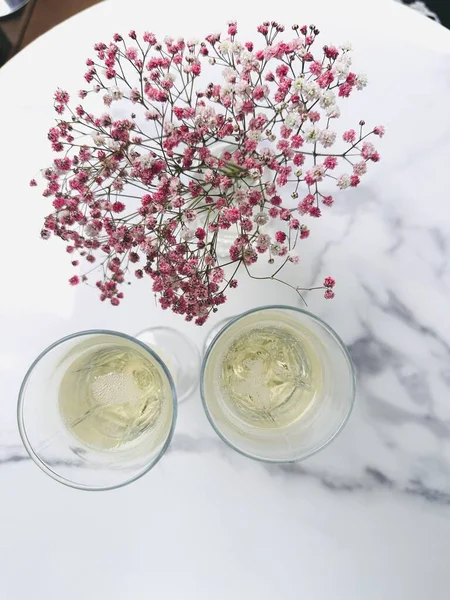 Caddedeki bir kafede masanın üstünde iki bardak şampanya ve pembe çiçekler. orta plan.
