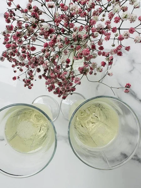 İki bardak şampanya ve pembe çiçekleri kapatın. Masanın üstünde, caddedeki bir kafede. . 