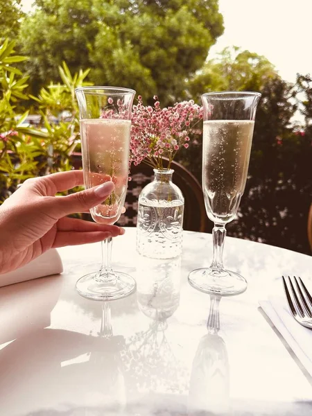 Kafkasyalı bir kızın elinde bir bardak şampanya, dışarıdaki kafede bir masada.. 