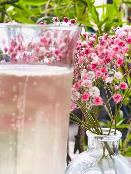 Caddedeki bir kafede masanın üstüne iki bardak şampanya ve pembe çiçek koy. . 