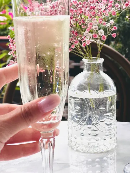Kafkasyalı bir kızın elinde bir bardak şampanya, dışarıdaki kafede bir masada.. 