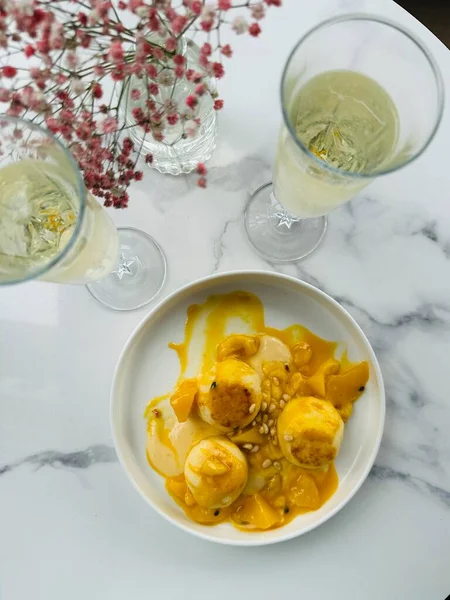 Kafamızın üstünden. Mango mus yanında dilimlenmiş mango, açık kafedeki masada iki bardak şampanya..