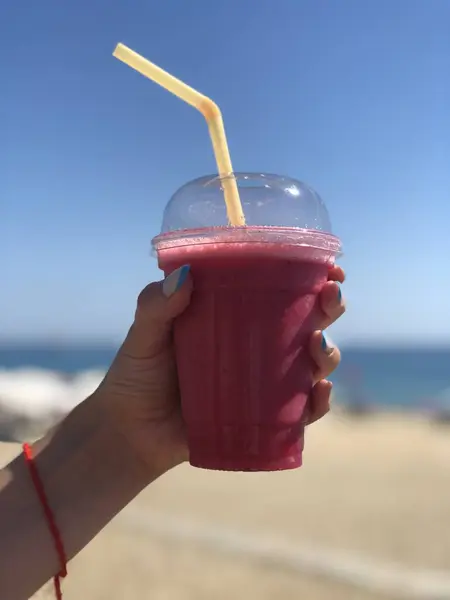 Deniz zemininde genç bir kızın elinde meyve püresi camı. Yakın çekim.